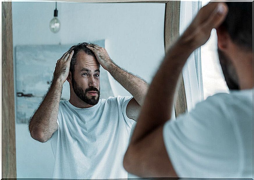 Man looking at his scalp in the mirror.