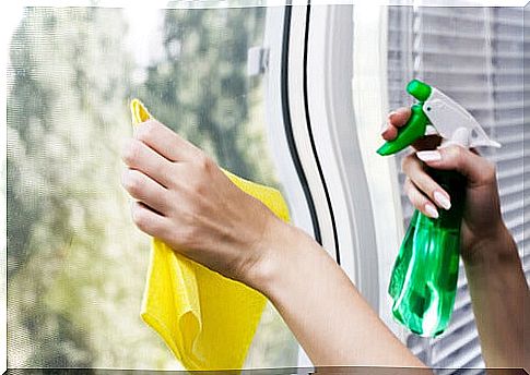 Hands cleaning the windows with a spray bottle and a cloth